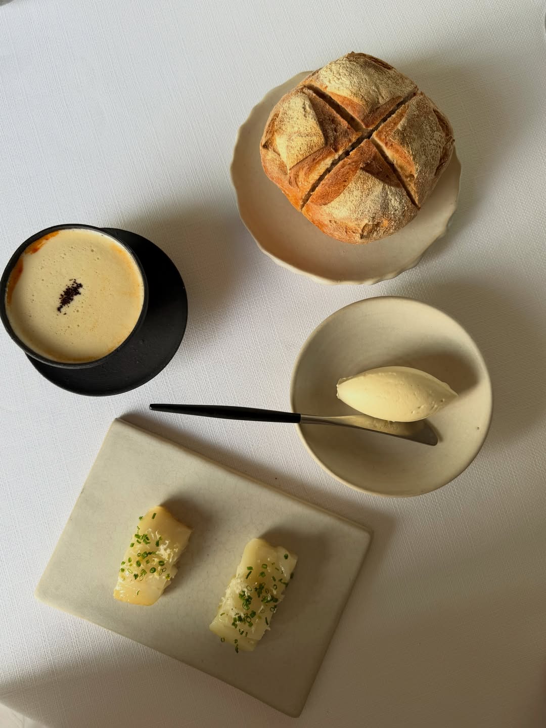 Het huisgemaakte zuurdesembrood, de boter en de gerookte schelvis die bij de garnalenbisque worden geserveerd, trekken het zilte karakter van het gerecht verder door.

Het zuurdesembrood wordt volledig in huis gebakken. De boter wordt gemaakt van lokaal geproduceerde melk en verrijkt met makreelkuit. Die wordt eerst gepekeld in zout en suiker en vervolgens een week lang elke dag twee uur gerookt, waardoor ze de geconcentreerde smaakdiepte van bottarga krijgt. Daarna wordt de kuit fijn geraspt en samen met Willems huisgemaakte makreelgarum en verse citroenzeste door de boter gemengd.

De boter is zilt en rokerig, met frisse toetsen van citrus. Ze wordt royaal op het warme zuurdesembrood gesmeerd en afgewerkt met gerookte schelvis—perfect om de laatste druppels bisque mee op te deppen.

_________________________

Served alongside the shrimp bisque, homemade sourdough bread, butter and smoked haddock extend the marine character of the dish.

The sourdough bread is baked in-house, while the butter is made with locally sourced milk and enriched with mackerel roe. The roe is cured in salt and sugar, then smoked for two hours each day over the course of a week—developing the concentrated depth of bottarga. It is finely grated into the butter with Willem’s homemade mackerel garum and fresh lemon zest.

Saline, smoky and lifted by citrus, the butter is spread generously over the warm sourdough and topped with smoked haddock—ideal for catching every last drop of the bisque.

#Willemhiele
#MichelinStar
#Worlds50best
