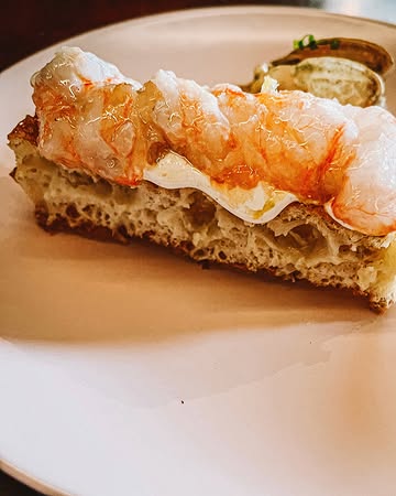 x @elders.gent - BIJNA 3.

🧑‍🍳 @tompauwelyn
🍇 @romydeconinck
❤️ @thomas_bontinck @clarafrancoiske @angeliquebeyens

Voorheen kreeg Milo mij nooit, maar dan ook echt nooit, mee naar de markt op het Van Beverenplein. Maar nu? Nu kunnen we spreken van een pre-Elders/Anders tijdperk, en een post.

Voorheen is niet meer nu, de keren dat ik naar de markt vlieg, zijn mijn aantal vingers allang voorbij. Een perfecte zondag wordt nu gedefinieerd, geschapen en vervolledigd door hén.

Tom en Romy hebben iets uniek gecreëerd. Uiteraard is het vééééél meer dan een zondags uitje met wijn, al dan niet à la carte uitlevingen, cocktails en tipsy naar huis stappen.

Nee, ik schrijf zogezegd niet over de pita, of de wafels met langoustines of coquilles. Niet over hoe kiezen bij de voor- en hoofdgerechten steeds weer een beetje verliezen is.
- Eerlijk hoe kan je nu kiezen tussen: Varkensspiering, wortel, gerookte appel; gekonfijte skrei, kooltjes, oester, weisaus of rissoto van zonnebloempit, aardpeer, burrata, eerlijk ik krijg er weer stress van -

Niet over het staren naar dat powerkoppel dat levensvreugde uitstraalt en een stukje foodiehemel personifieert. Niet over de eerste bezoekjes van Charlie, Bonnie en binnenkort Donna die blijven en zullen blijven hangen. Noch de duizenden selfies in het toilet (een ware collectie op zich).

Ik schrijf zogezegd niet over de overheerlijke, zelfgemaakte pasta’s: zoals spaghette alla chitarra met oa maitake of parpadelle al nero. Of zwijg ik dan maar over die aubergine met die gerookte dooier, holy moly.

Maar zie mij hier nu schrijven en nu ik mij geen pre-tijd meer voorstellen kan, maakt de gedachte aan een non-gedachte mij wel gelukkig.

(Bijna) 3 jaar Elders. 3 jaar happy Belly.

#elders #gent #gent #belly #lolosbelly #bijna3 #liefde #food #altijdhonger #charlieweet #vanbeverenplein